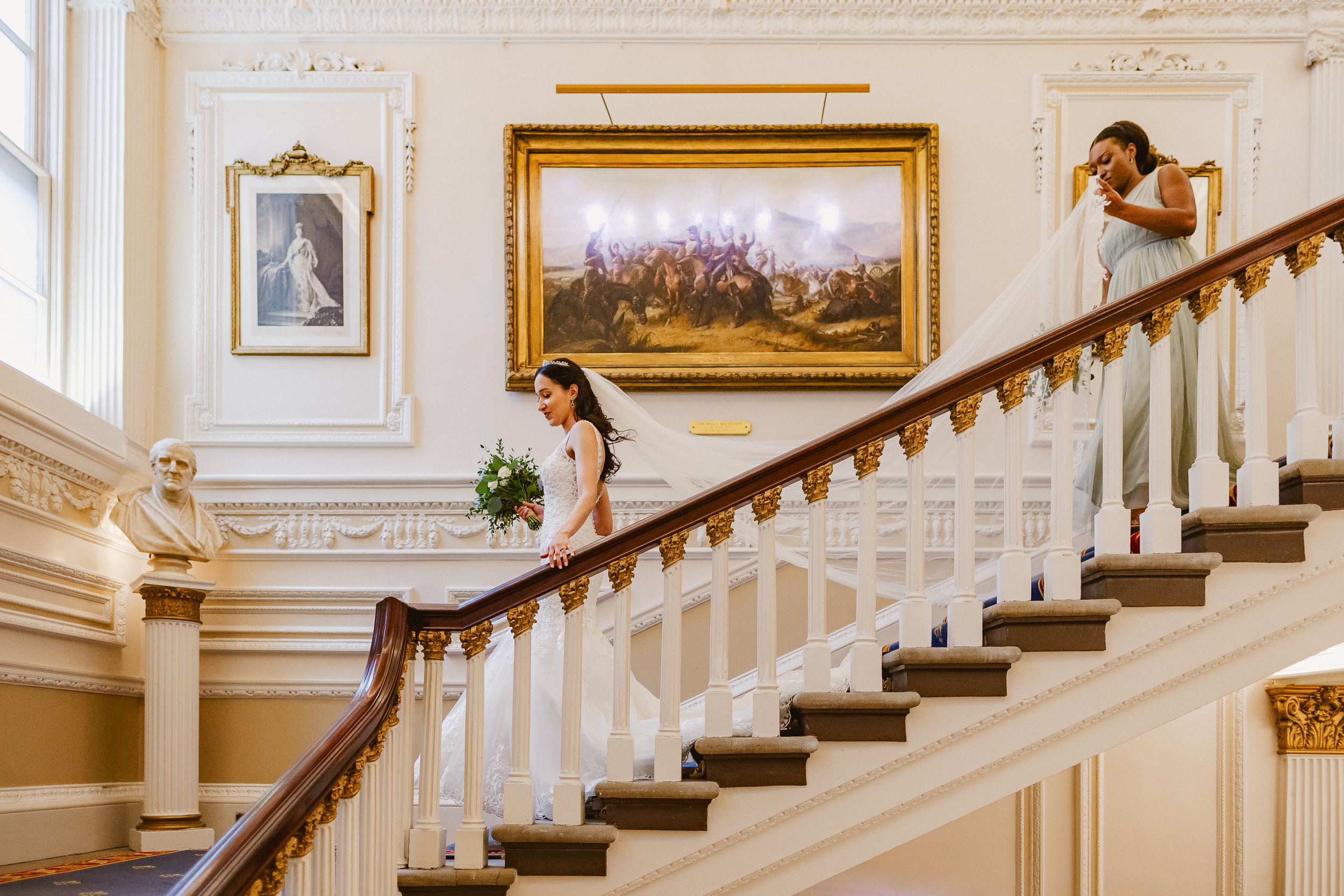 Bride Descending Stairs at The In and Out Club – Wedding Moment 7 Bride being gently helped downstairs inside The In and Out Club during wedding preparations