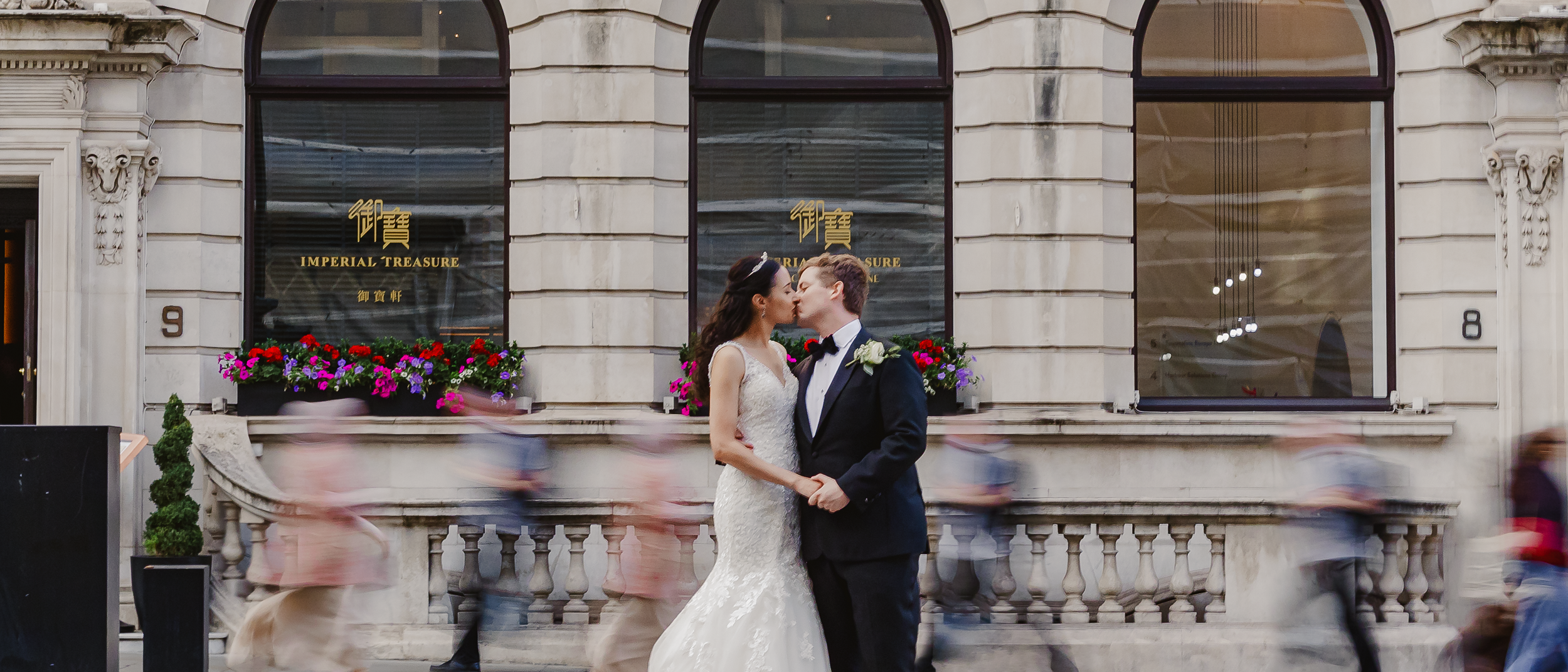 London Wedding Photography Bride and Groom in Motion Amidst City Traffic and groom standing in the middle of a street with fast-moving cars passing by during wedding day photoshoot