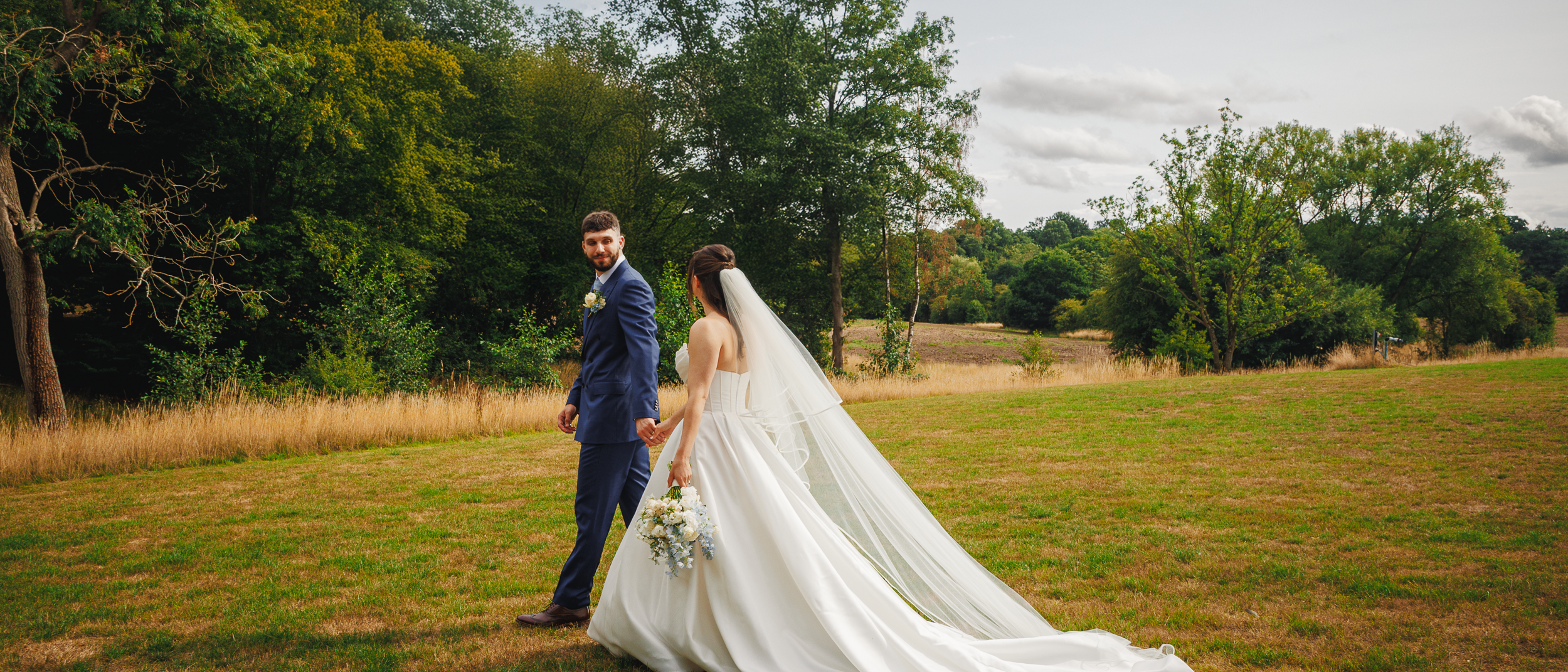 newlywed couple walking away hand in hand at Brook Farm wedding venue
