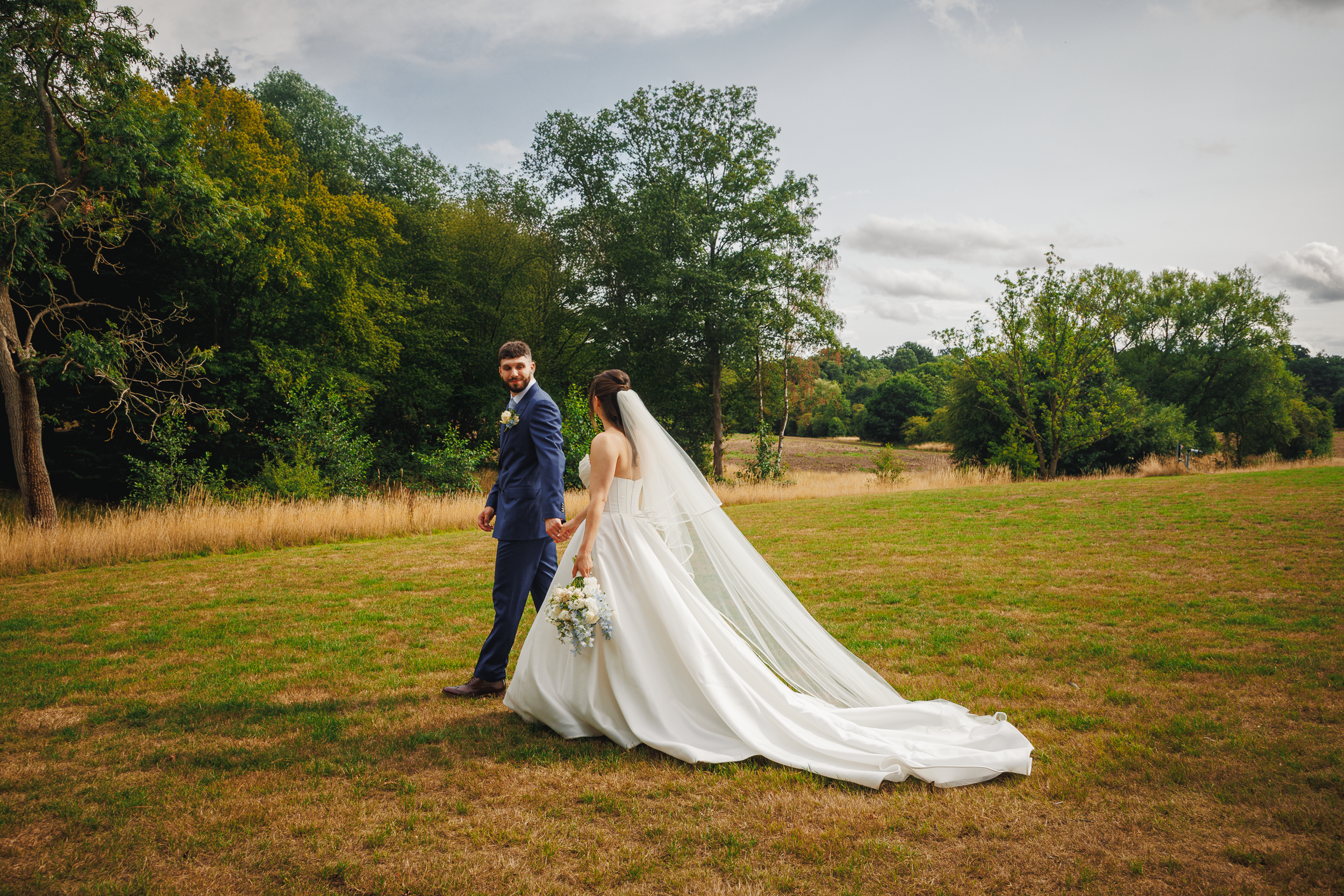A Real Wedding at Brook Farm Cuffley: Anna & Tommy’s Elegant Lakeside Celebration 2 newlywed couple walking away hand in hand at Brook Farm wedding venue