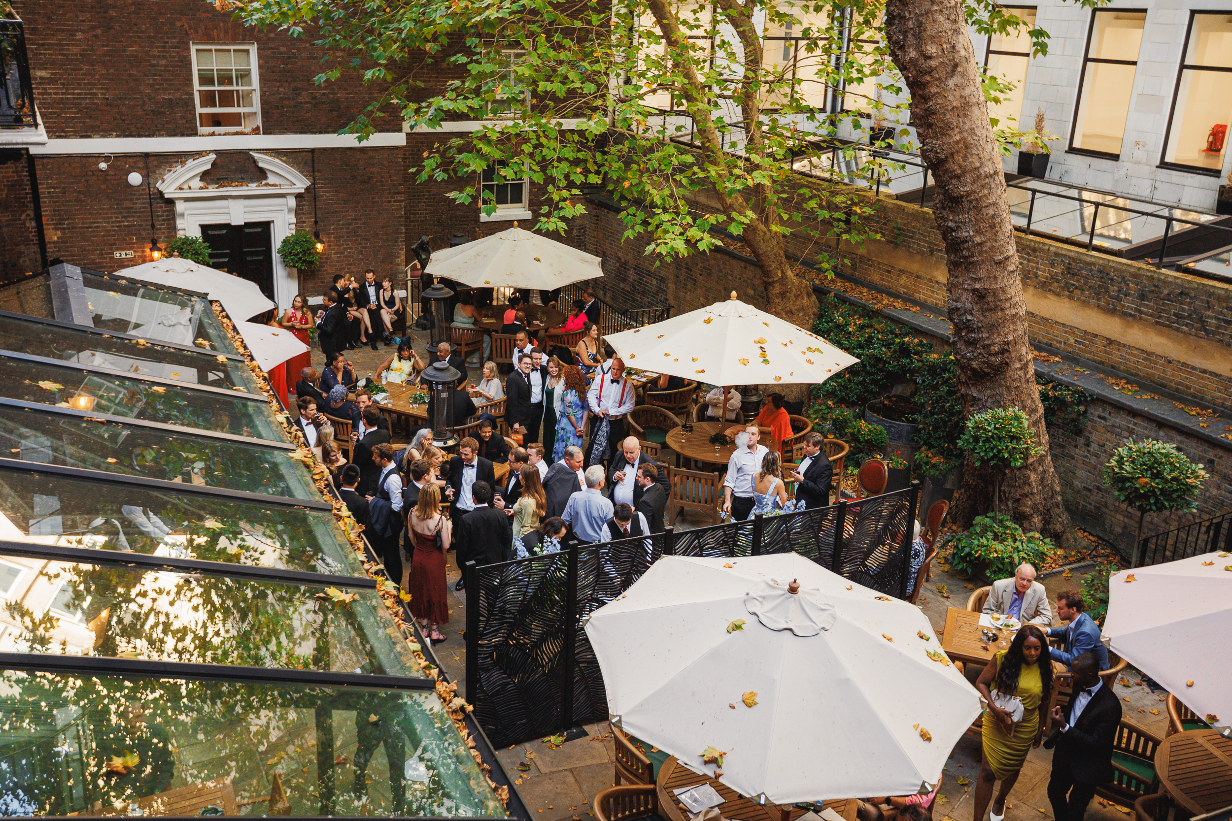 Guests Enjoying Drinks in the Courtyard of the In and Out Club 12 Wedding guests socializing and enjoying drinks outdoors in the courtyard of the In and Out Club